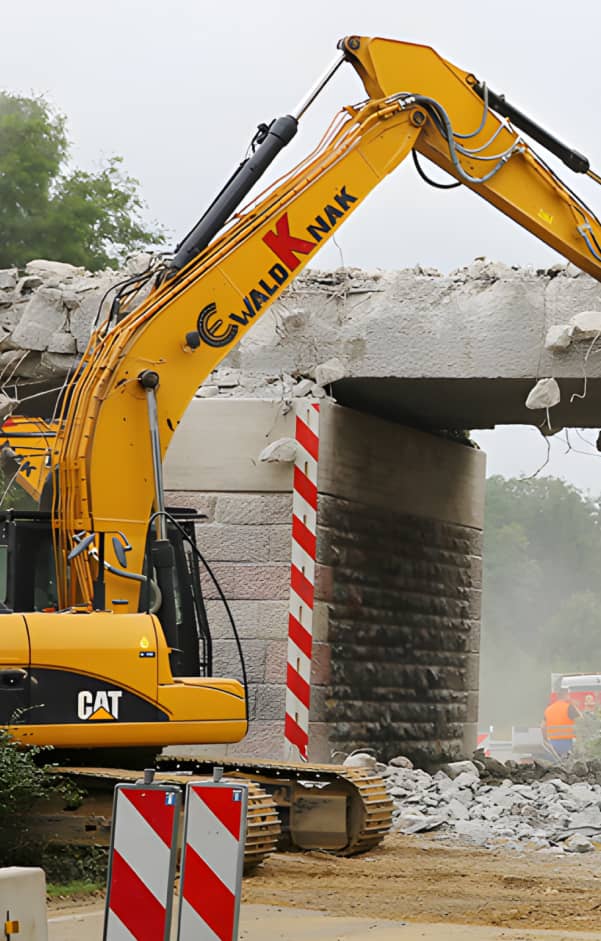 Ein Bagger von Ewald Knak beim kontrollierten Rückbau einer Betonbrücke